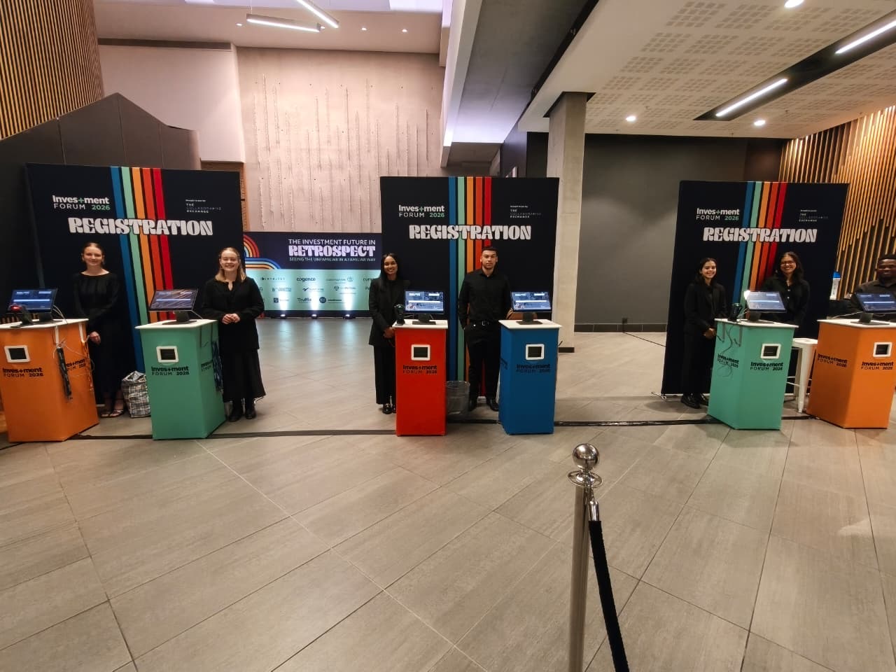 Colourful branded registration kiosks and staff at Investment Forum 2026
